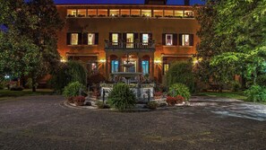 Un hotel con una fuente central, un patio y un edificio con múltiples ventanas y balcones.