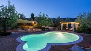 A swimming pool with a wooden deck, lounge chairs, and a pergola with string lights. - Ar-l123-tebr0at - Buca Delle Fate 8 (Terranuova Bracciolini)