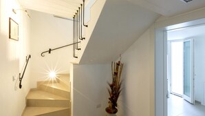 Una escalera de diseño moderno, un aplique de pared y un jarrón decorativo con ramas.