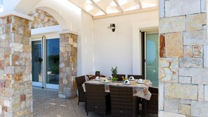 Un patio al aire libre con paredes de piedra, muebles de mimbre y una mesa dispuesta para una comida.