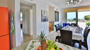 Comedor con una mesa dispuesta para cuatro personas, un frutero sobre la mesa y vistas al exterior.