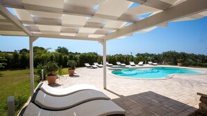 Una piscina al aire libre techada con sillas de descanso y plantas en macetas.