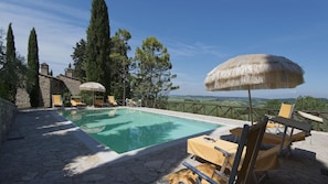 A pool with lounge chairs and umbrellas, surrounded by stone walls and trees, with a view of the countryside. - Pi-m126-pofr0at - Frantusa 6 2 (Volterra)