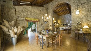 A rustic dining area with stone walls, wooden beams, and a stone floor. There is a table set for four with chairs, a chandelier, and a potted plant with pampas grass. - Fi-m408-snoc0at - Casabianca 12 (Barberino Tavarnelle)