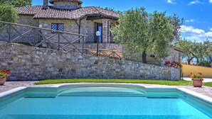 A stone building with a tiled roof, a swimming pool, and potted plants. - Tr-f457-mcas0as - Colle del Sole 7 1 (Montecastrilli)