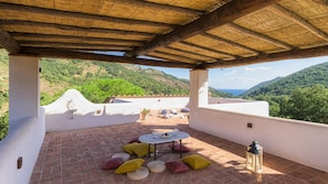 A covered outdoor patio with a table and cushions, overlooking a mountainous landscape. - Villa Zaca 6 in Rio Marina (Rio)