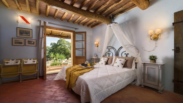A bedroom with a large bed, a wooden ceiling, a nightstand, and a view of the outdoors. - Villa Zaca 6 in Rio Marina (Rio)