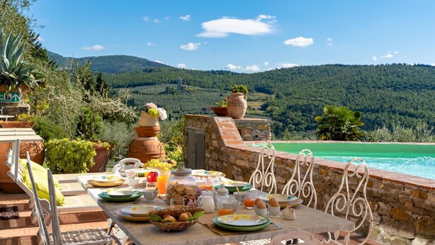 A breakfast table with a view of a mountain and a pool.