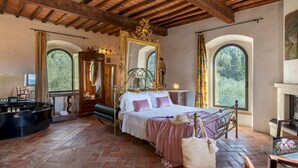 A bedroom with a bed, a piano, a mirror, and a fireplace.