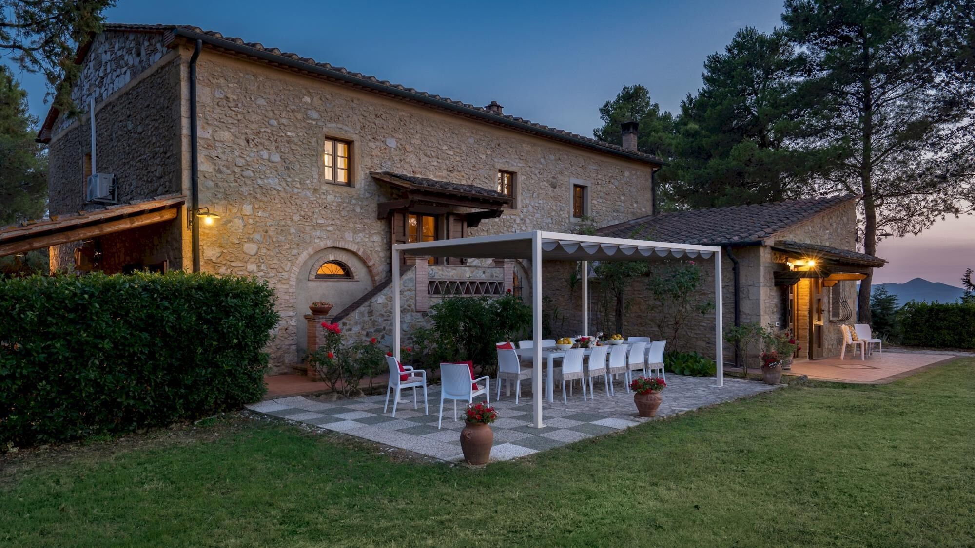 A stone building with a covered outdoor dining area, a staircase, and a view of the mountains.