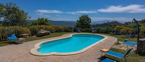 A swimming pool with lounge chairs and a stone patio.