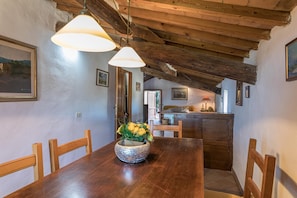 Enjoy meals in this cozy dining area with a rustic table and chairs, surrounded by framed pictures and a wooden cabinet.
