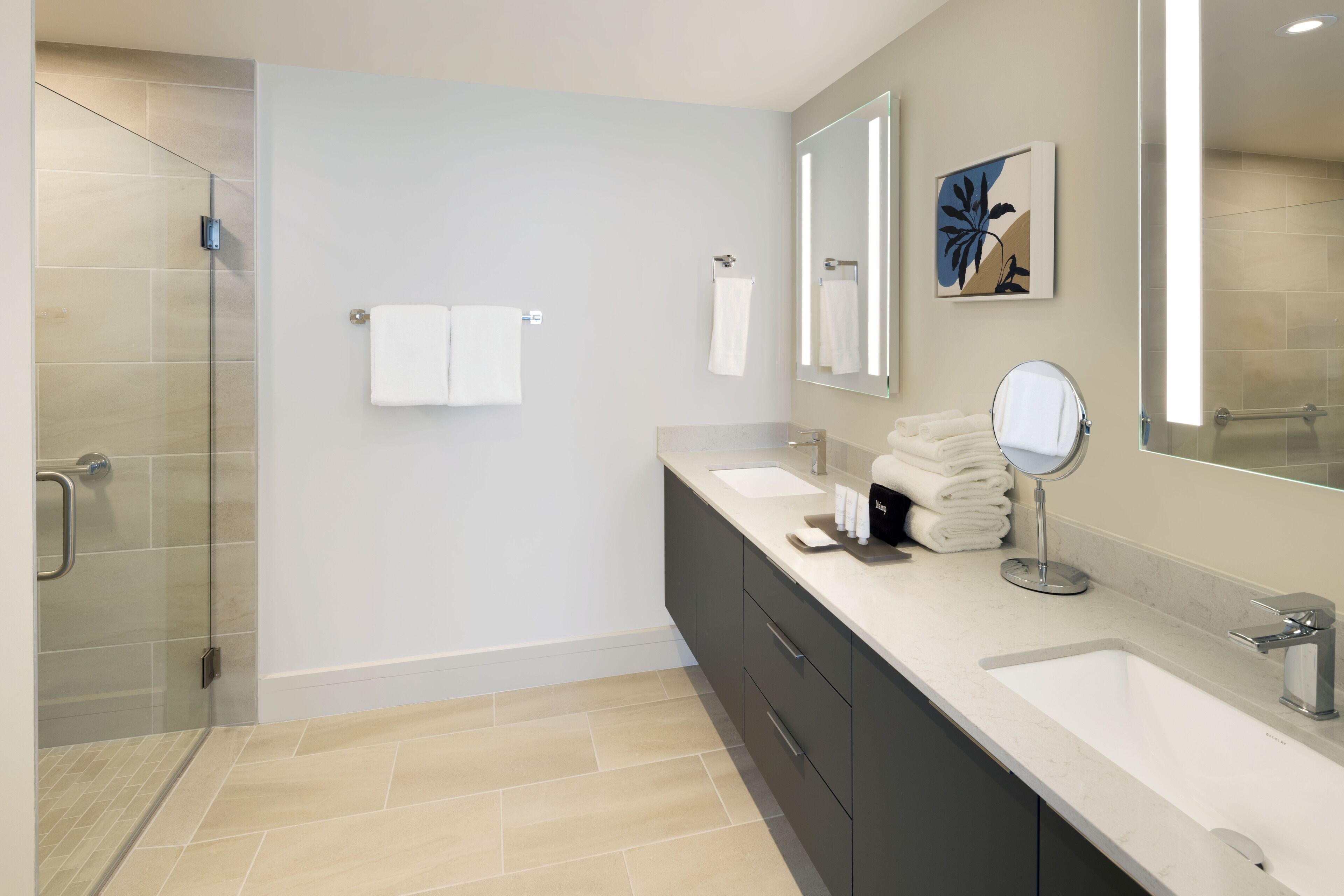 A modern bathroom with a glass shower enclosure, a double sink vanity, and a large mirror.