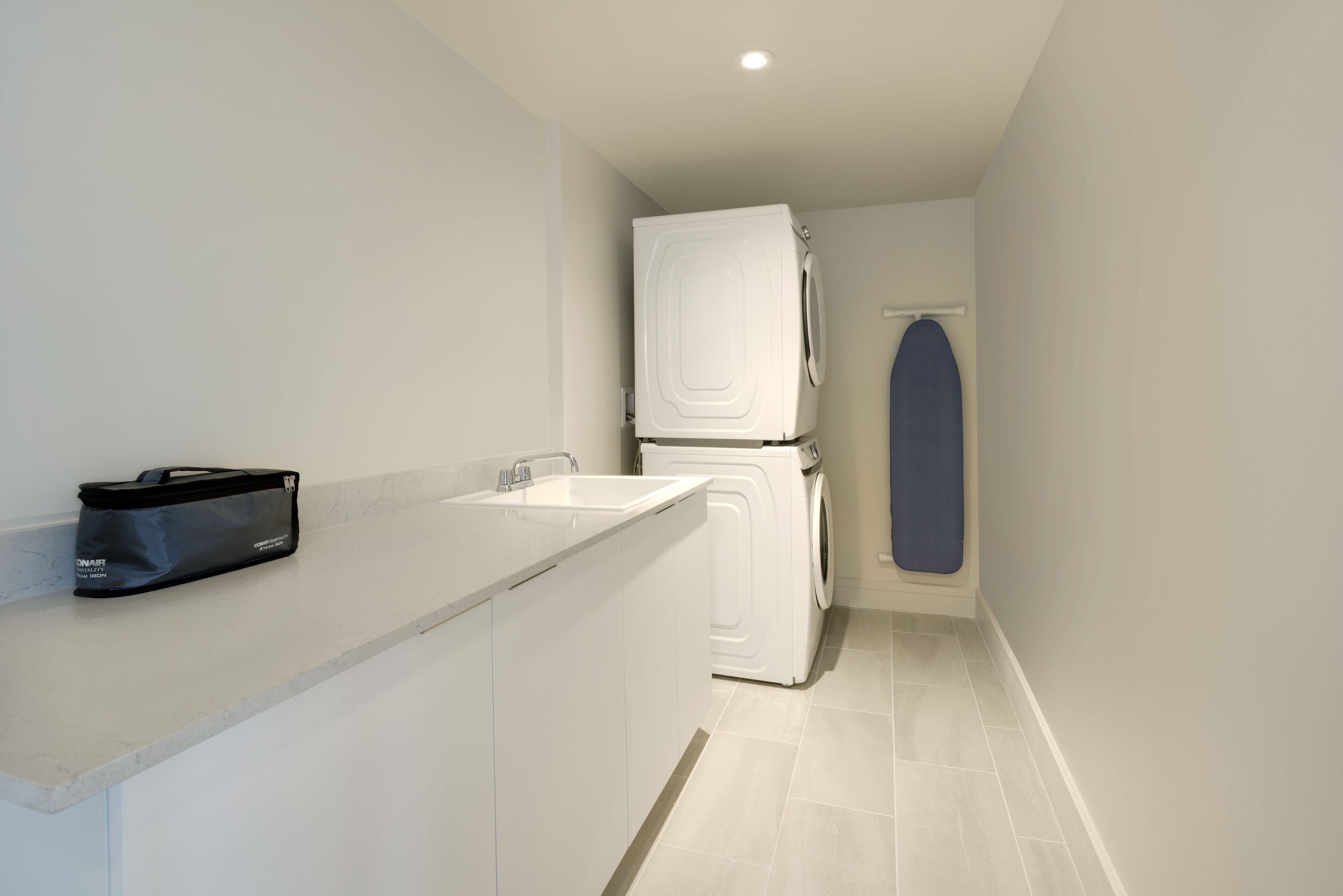 Una cocina compacta con encimera blanca, lavadora y una toalla azul colgada en una puerta.