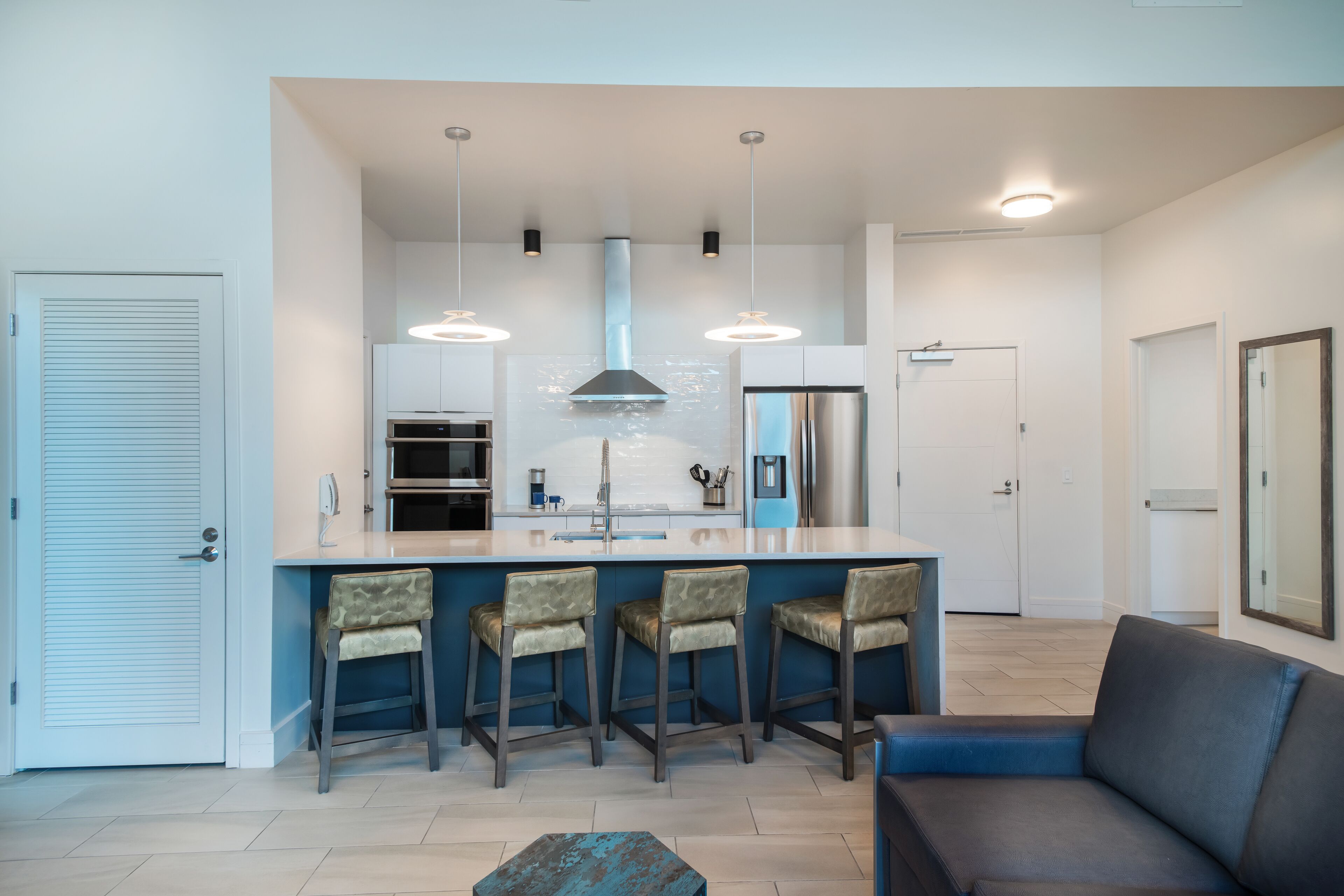 A modern kitchen with a central island, bar stools, and pendant lighting.