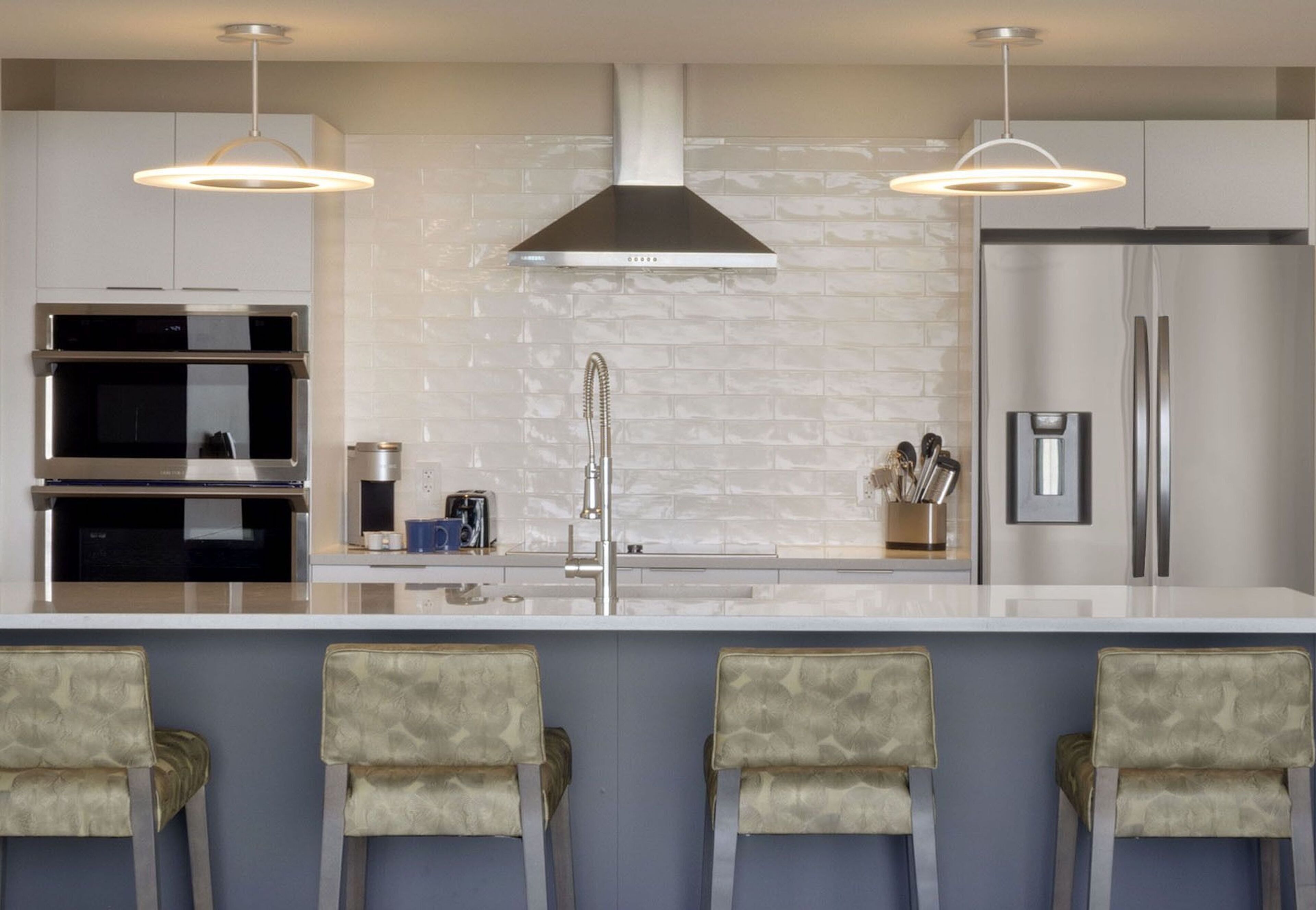Una cocina moderna con una isla central, electrodomésticos de acero inoxidable y taburetes de bar.