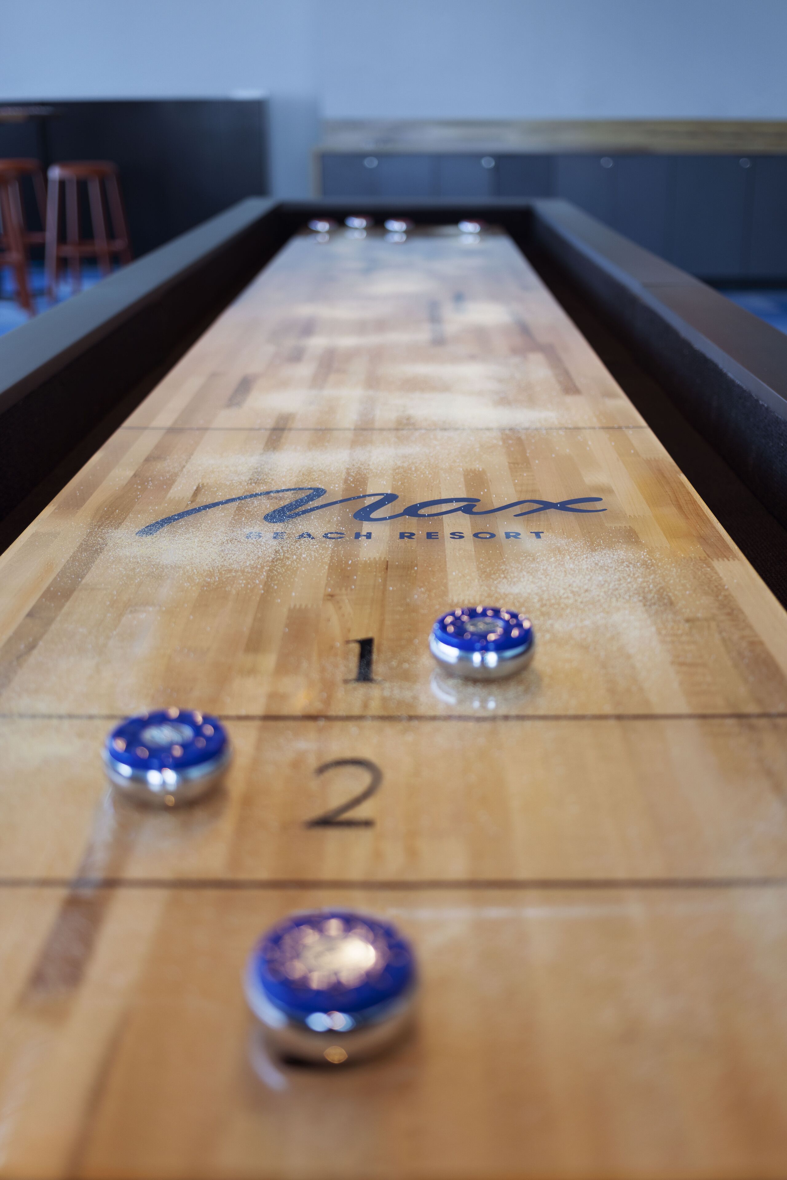 A shuffleboard table with the numbers 1 and 2 visible, and the name "Beach Resort" written on it.