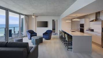 Une cuisine moderne dotée d’un grand îlot central, de tabourets de bar et offrant une vue sur la mer.