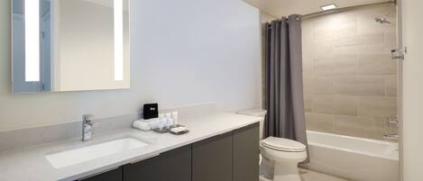 Un baño moderno con un espejo grande, dos lavamanos, un inodoro y una bañera.