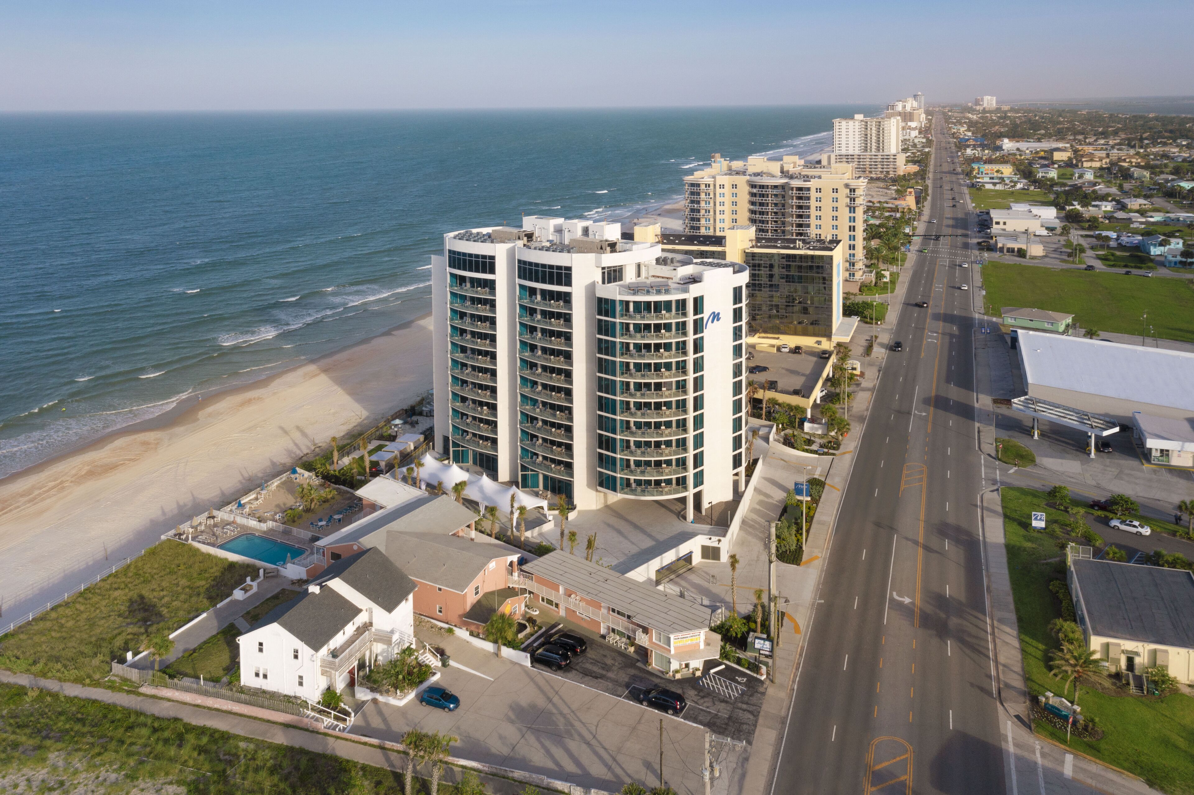 Hotel alto com várias varandas com vista para a praia e o oceano.