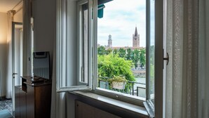 Ett rum med ett stort fönster, ett element och ett skrivbord med en stol.