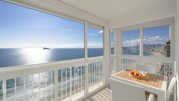 A balcony with a view of the sea and cityscape, featuring a table with breakfast items. - Brilliant Panoramic Front line apartment Veracruz Levante (R099) (Benidorm)