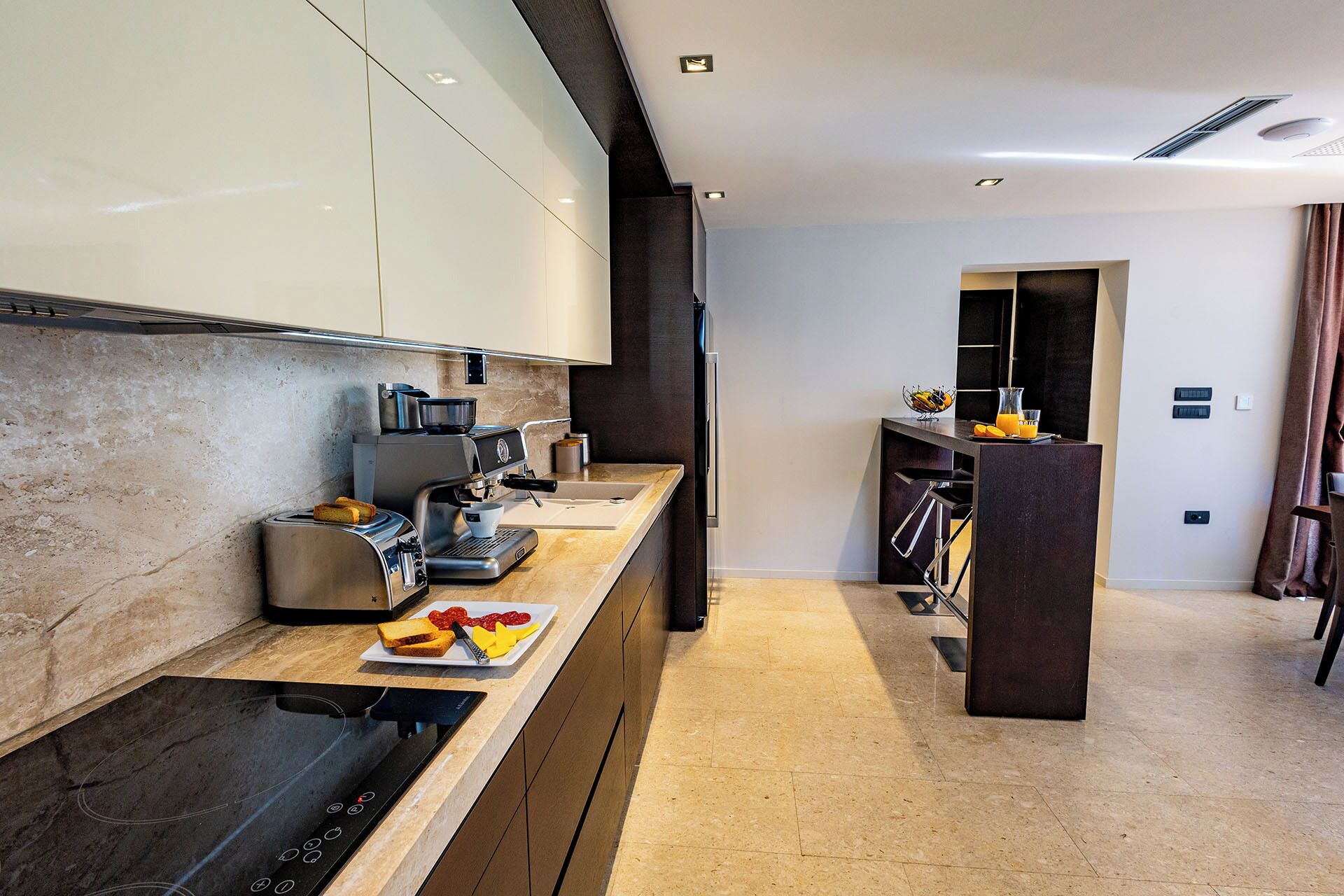 Een moderne keuken met een ingebouwde espressomachine, een broodrooster en een ontbijtbord met toast en fruit.