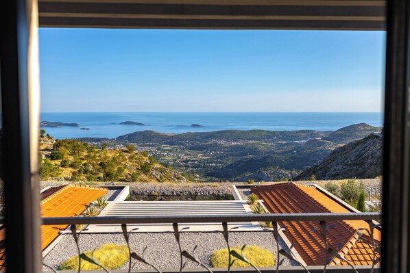 A view from a balcony overlooking a coastal landscape with a clear sky.