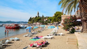 Una spiaggia con lettini, ombrelloni e barche.
