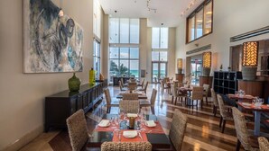 A spacious dining area with high ceilings and large windows, offering views of the ocean. - Private Beachfront Condominium with Resort and Amenities Access (Sunny Isles Beach)