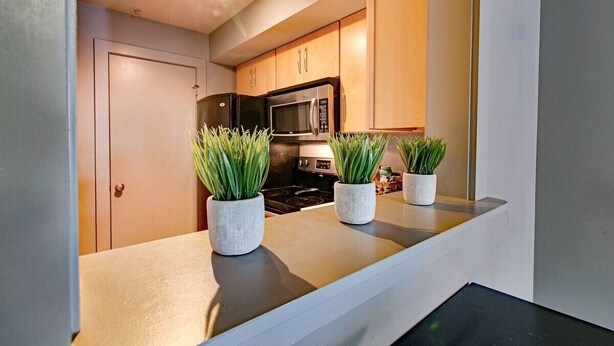 A kitchen with wooden cabinets, a microwave, and two potted plants on the countertop.