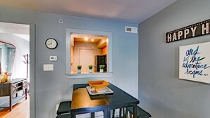 A dining area with a table, chairs, a clock, a window, and a motivational quote on the wall.