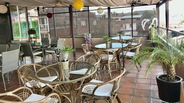An outdoor patio with wicker furniture, potted plants, and a view of buildings in the background. - House of Stairs, Pátzcuaro, Michoacán (Pátzcuaro)