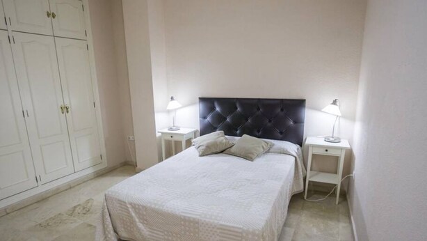 Une chambre à coucher avec un lit, deux tables de chevet avec des lampes et une armoire.