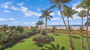 Une pelouse bien entretenue, agrémentée de palmiers et offrant une vue sur la plage.