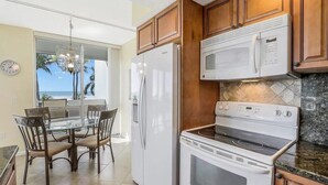 Une cuisine avec des meubles en bois, un réfrigérateur blanc, un four à micro-ondes et une cuisinière.