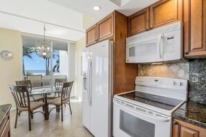 Una cocina con armarios de madera, un refrigerador blanco, un microondas y una estufa.