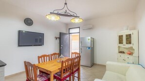 A compact living space with a dining area, a sofa, a TV, a refrigerator, and a cabinet. - [Beach-Seafront 5 Stars] Comfortable Holiday Home (Avola)