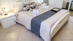 A neatly made bed with a gray throw blanket, two rolled towels, and two wine glasses on a tray. - [Beach-Seafront 5 Stars] Comfortable Holiday Home (Avola)