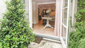 Une véranda avec une table et des chaises, un mur en pierre et une vue sur le jardin.
