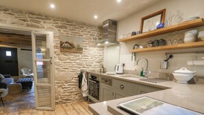 Une cuisine chaleureuse avec des murs en pierre, un plancher en bois et un coin repas offrant une vue agréable.