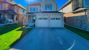 A two-story house with a garage, a stone facade, and a well-maintained lawn. - 🍷 Luxury Pond House, 10 minutes to Niagara Falls (Thorold)