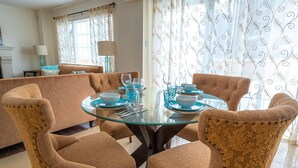 A dining area with a round glass table set for four, surrounded by upholstered chairs with a floral pattern. - 🍷 Luxury Pond House, 10 minutes to Niagara Falls (Thorold)