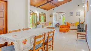 A spacious living area with a dining table set for four, wooden chairs, and a sofa.