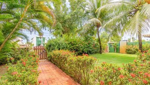 A paved garden path with lush greenery and flowering plants.