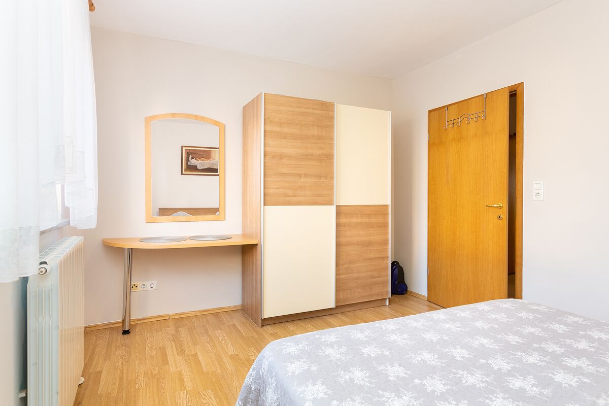 Une chambre à coucher avec un lit, une armoire, une table de chevet et un radiateur.
