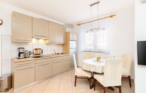 A modern kitchen with beige cabinets, a coffee maker, and a dining table with chairs. - Istriensonne 0034 - Ferienwohnung Vilic-2 (Medulin)