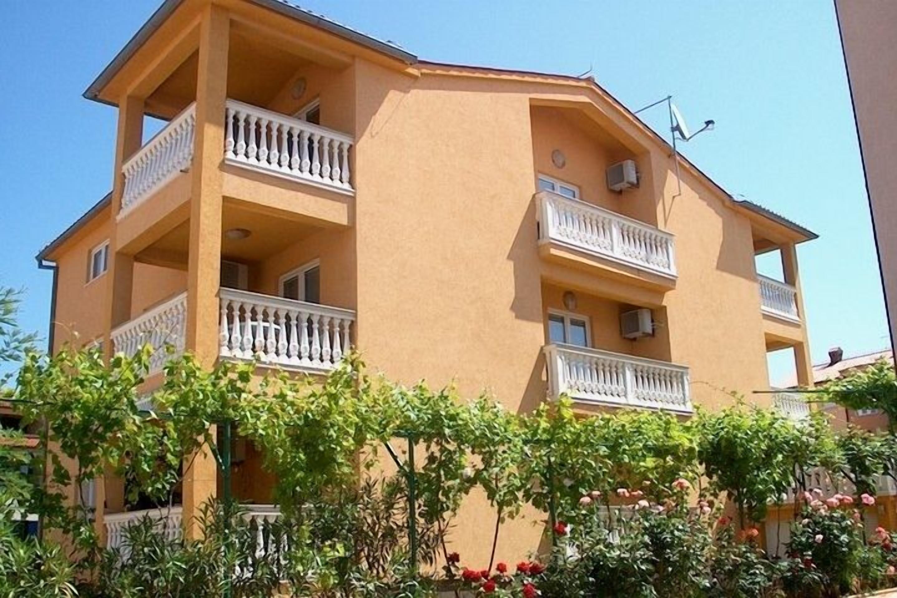 Un edificio a più piani con balconi, immerso nel verde.