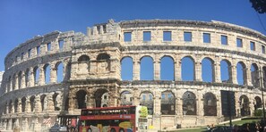 Ein historisches, steinernes Amphitheater mit mehreren, in Terrassen angelegten Arkadengängen und Sitzreihen.
