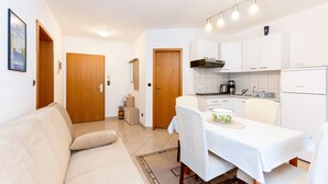 Une cuisine compacte avec des meubles blancs, une machine à café et un coin repas avec une table dressée pour deux personnes.
